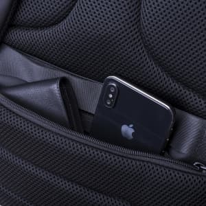 A black smartphone and wallet are secured in the compartment of a padded, mesh backpack. The backpack features a logo.