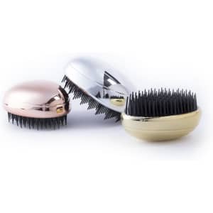 Three hairbrushes in rose gold, silver, and gold, each featuring black bristles, displayed together.