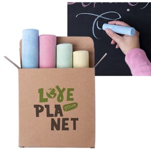 A box containing large, pastel-coloured chalk sticks alongside a hand writing on a blackboard, featuring a logo.