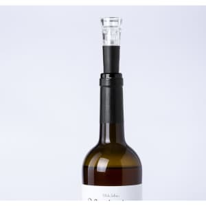 A drink bottle with a sleek black vacuum bottle stopper, topped with a clear glass section, showcasing an elegant design.
