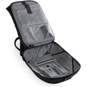 A black backpack opened to reveal grey interior compartments and pockets, featuring a logo on the exterior.
