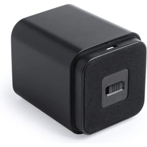 A compact black speaker with a square shape and a switch on the front. It features a minimalist design and a logo.