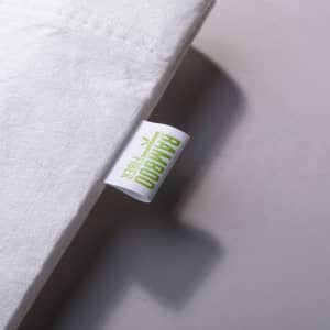 A close-up of a white tote bag featuring a label with a logo, made from bamboo fibre.