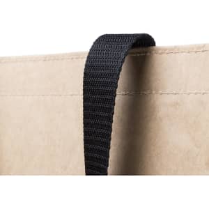 A close-up of a tan reusable grocery bag with a black strap. The bag has a simple, minimalist design.