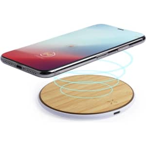 A wireless charger with a bamboo finish and a smartphone positioned above, emitting blue charging indicators.