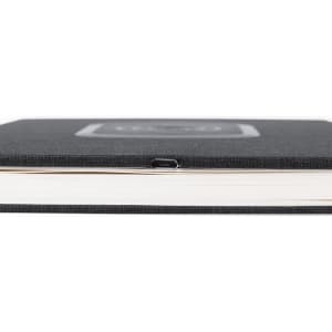 A black notepad with a smooth cover and a USB charging port on the side, featuring a sleek design.