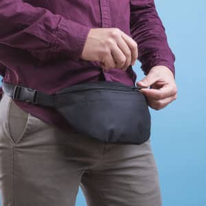 A black waist bag with a zippered pocket, worn around the waist, features an adjustable strap.