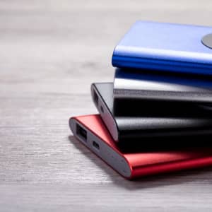 A stack of power banks in blue, black, and red, featuring a sleek design and a logo on the surface.