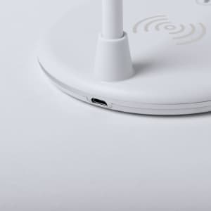 A white multifunction lamp with a circular base and a USB port, featuring wireless charging symbols on the surface.