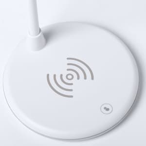 A white multifunction lamp base with a wireless charging area and a small branding logo.