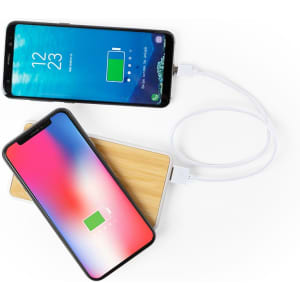 A power bank with a wooden design, connected to two smartphones via charging cables.