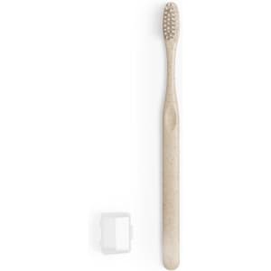 A toothbrush in a soft beige colour accompanied by a transparent travel case. The toothbrush has textured bristles and a slim design.
