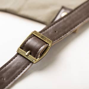 A brown belt buckle detail from a tan Vurcex apron, featuring a sturdy leather strap.