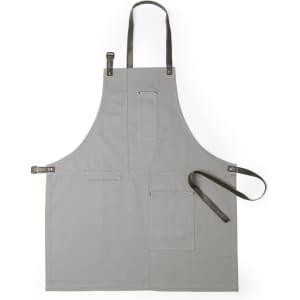 A grey apron with leather straps, featuring multiple pockets and adjustable fittings. It has a logo on it.
