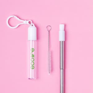A drink bottle with a transparent casing and a silver straw, accompanied by a cleaning brush and a clip attachment.