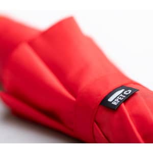 A red umbrella with a folded design and a tag featuring a logo.