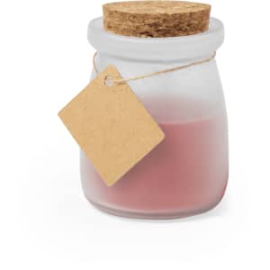 A frosted glass jar candle with a cork lid, filled with pink wax, and attached to a simple tag.