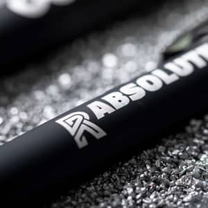 A set of metal pens featuring a sleek black design with a logo. The background contains shiny metallic shavings.