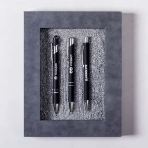 A presentation box containing three black metal pens displayed on a textured grey background.