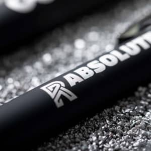 A close-up of a black stylus pen with a metallic logo on a textured silver background.