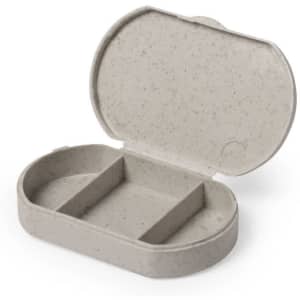 A grey pillbox with an oval shape, featuring three compartments and a hinged lid. It has a subtle speckled texture.