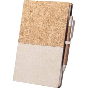 A notepad with a cork top section and a light fabric bottom, accompanied by a pen held in a holder.
