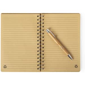 A brown spiral-bound notebook with lined pages and a silver pen resting on it. The notebook features a logo.