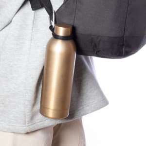 A gold drink bottle attached to a black bag strap, set against a light background.