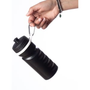 A black drink bottle with a textured grip, held by a hand using a metal carabiner.