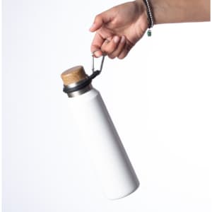 A white drink bottle with a cork stopper is held by a hand, featuring a metal clasp for attachment.