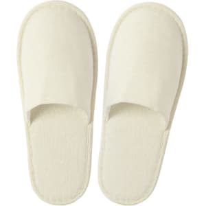 A pair of cream-coloured slippers with a simple, open-toe design. The slippers feature a soft fabric texture and have a logo.