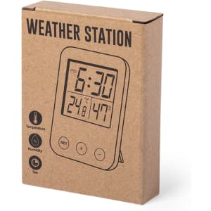 A weather station in a cardboard box featuring a digital display for time, temperature, and humidity. The box has a logo.