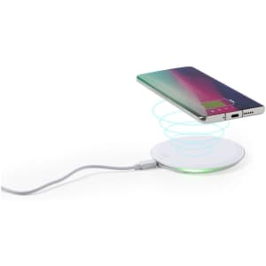 A wireless charger in white with a phone positioned above, displaying an illuminated charging indicator.