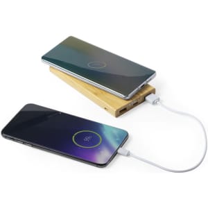 A wooden power bank with a sleek design, charging two mobile phones simultaneously.