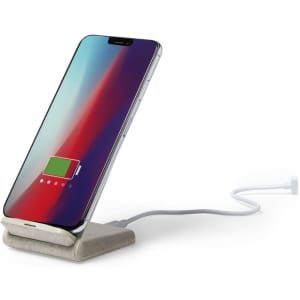 A wireless charger in grey with a phone placed upright, showing a battery charging indicator on the screen.
