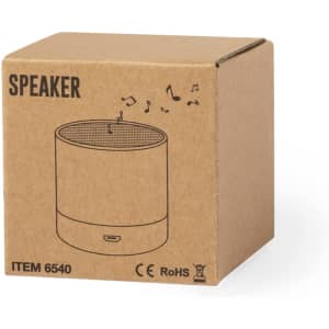 A brown cardboard box containing a round speaker design with a mesh top, featuring music note illustrations and a logo.