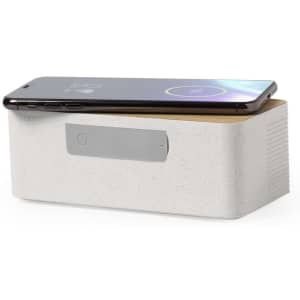A wireless charger speaker in white with a wooden top, holding a smartphone on its surface, featuring a logo.
