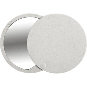 A round pocket mirror in a pale grey casing, featuring a reflective surface and a small button clasp.