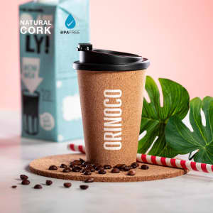 A drink bottle featuring a natural cork design with a black lid, placed on a cork coaster with coffee beans.