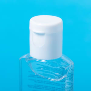 A clear hand sanitiser bottle with a white flip-top cap, set against a blue background.