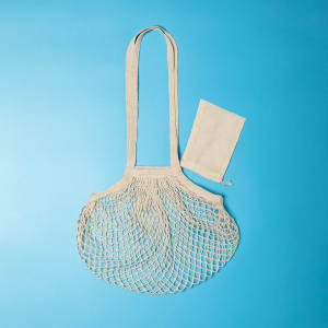 A foldable beige tote bag with a netted design, accompanied by a matching pouch.