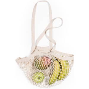 A cream-coloured foldable tote bag made of mesh, filled with green apples and bananas. It has a logo on it.