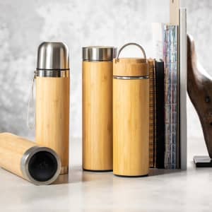 A drink bottle set featuring bamboo and stainless steel flasks in natural tones, accompanied by a book and decor items.