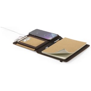 A brown notepad with a smartphone charging wirelessly, featuring pockets for cards and a pen holder.