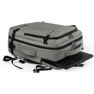 A grey document bag backpack with zippers and straps, resting beside a laptop. It features a logo on the side.