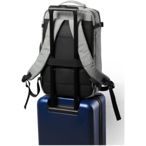 A grey backpack with adjustable straps resting on a blue suitcase, featuring a handle for easy transport.