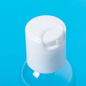 A clear bottle of hand sanitiser with a white pump top, set against a blue background.