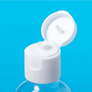 A clear bottle of hydroalcoholic gel with a white cap opened, set against a bright blue background.