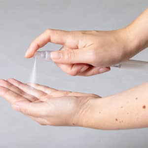 A clear spray pen dispensing a fine mist into an open palm, showcasing a simple and functional design.