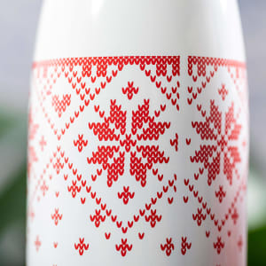 A drink bottle in white featuring a red patterned design with geometric shapes and a logo.